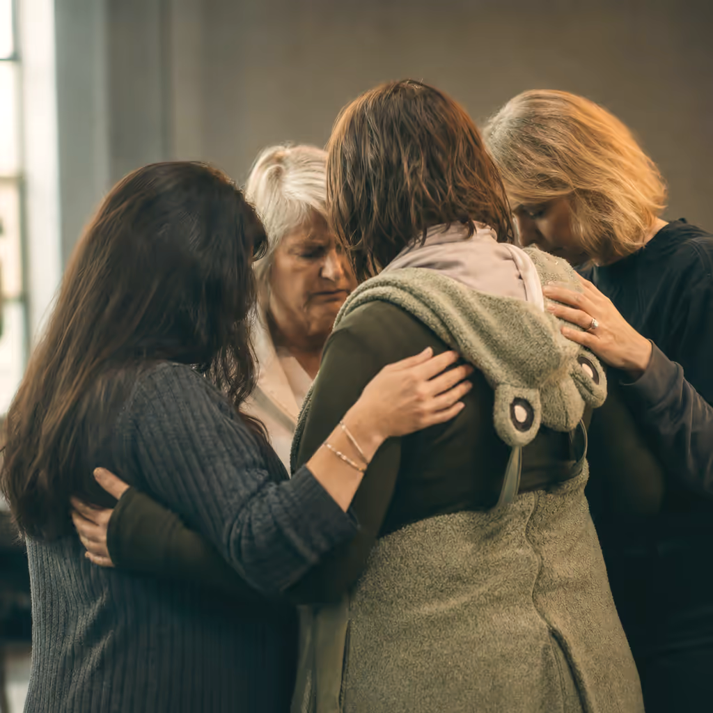 A group praying together with arms around each other