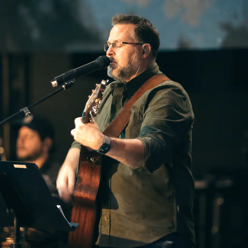 A worship leader playing acoustic guitar