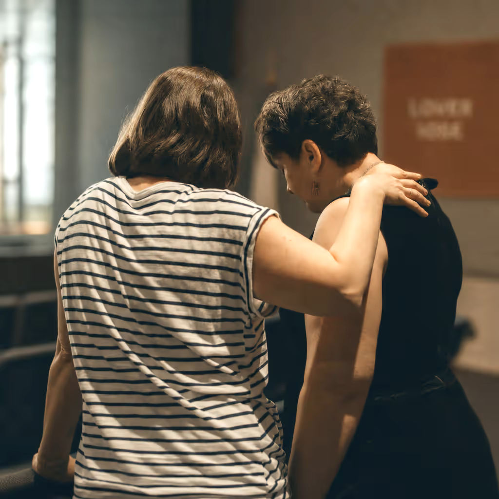 Two women standing closely, praying together