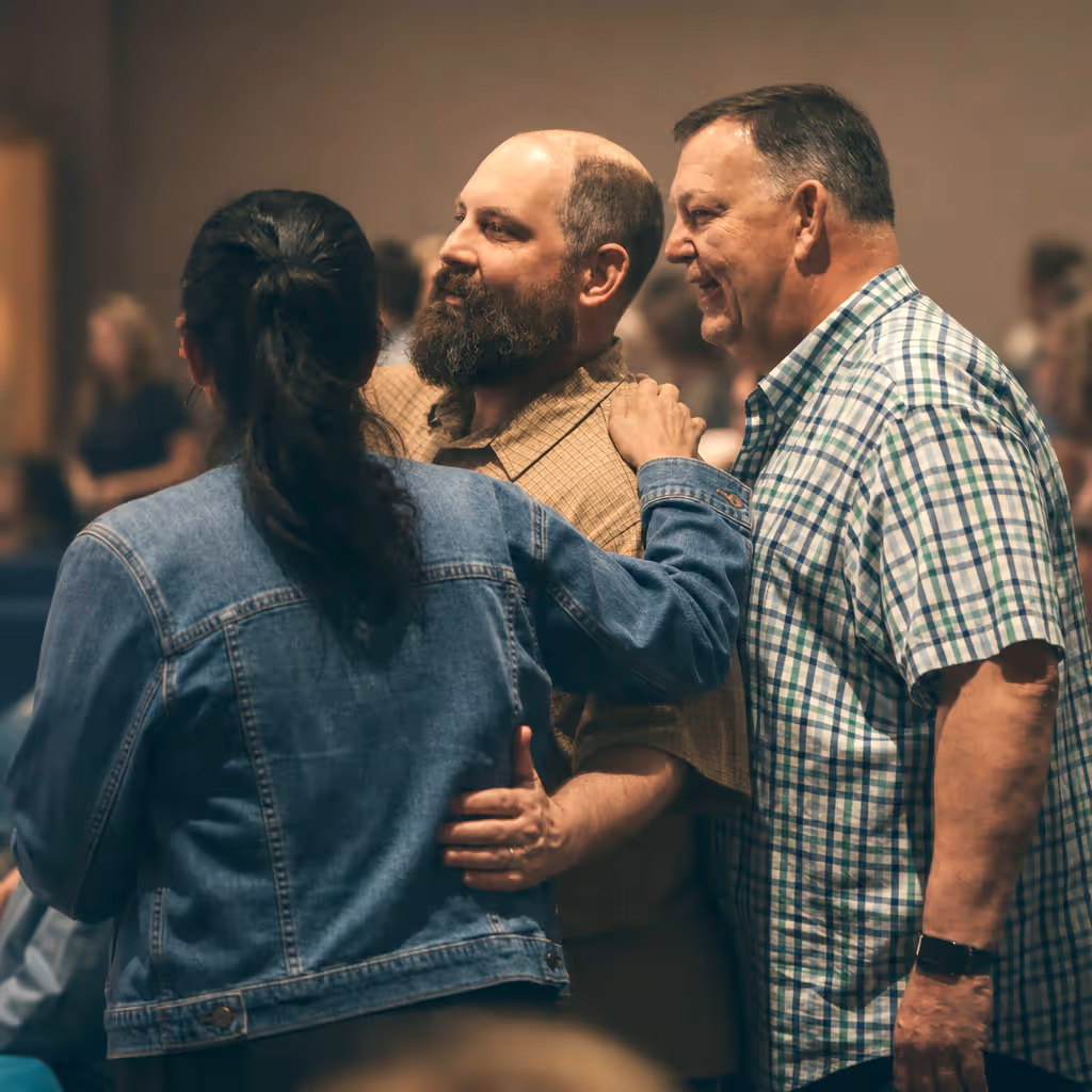 Three adults greeting one another in worship